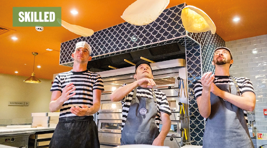 Pizza Express staff throwing pizza bases in the air